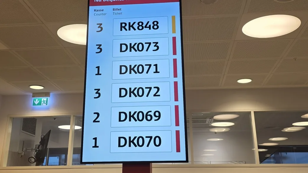 Oversigtstavle med aktuelle kønumre på DSBs billetkontor i Odense