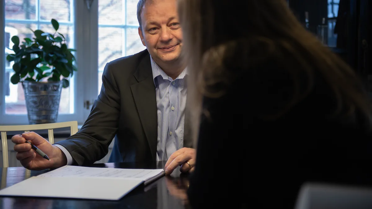 Henrik Klit Andersen sidder ved et bord over for en kunde og gennemgår et dokument
